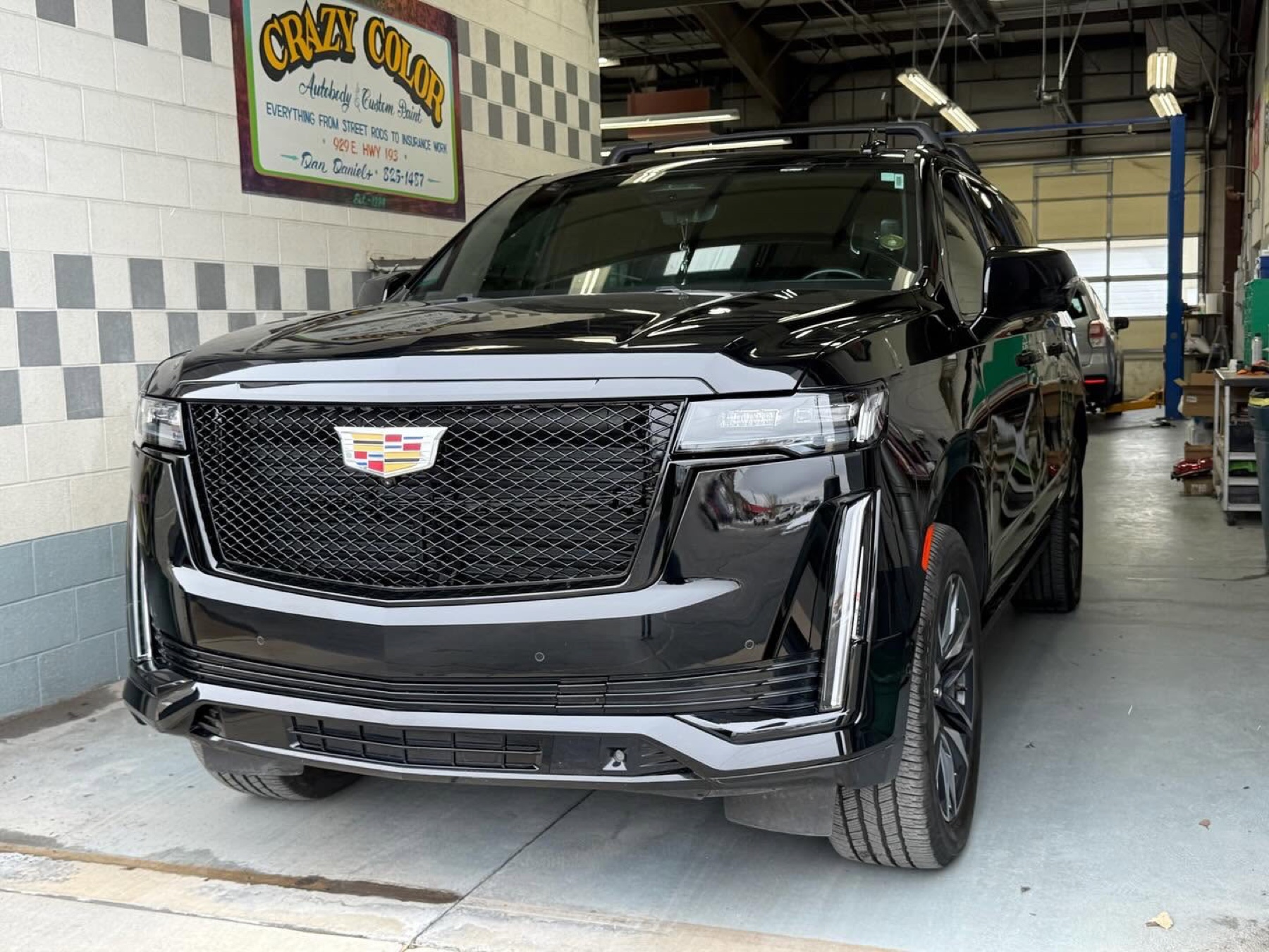 Finished black Cadillac SUV inside the Crazy Color shop