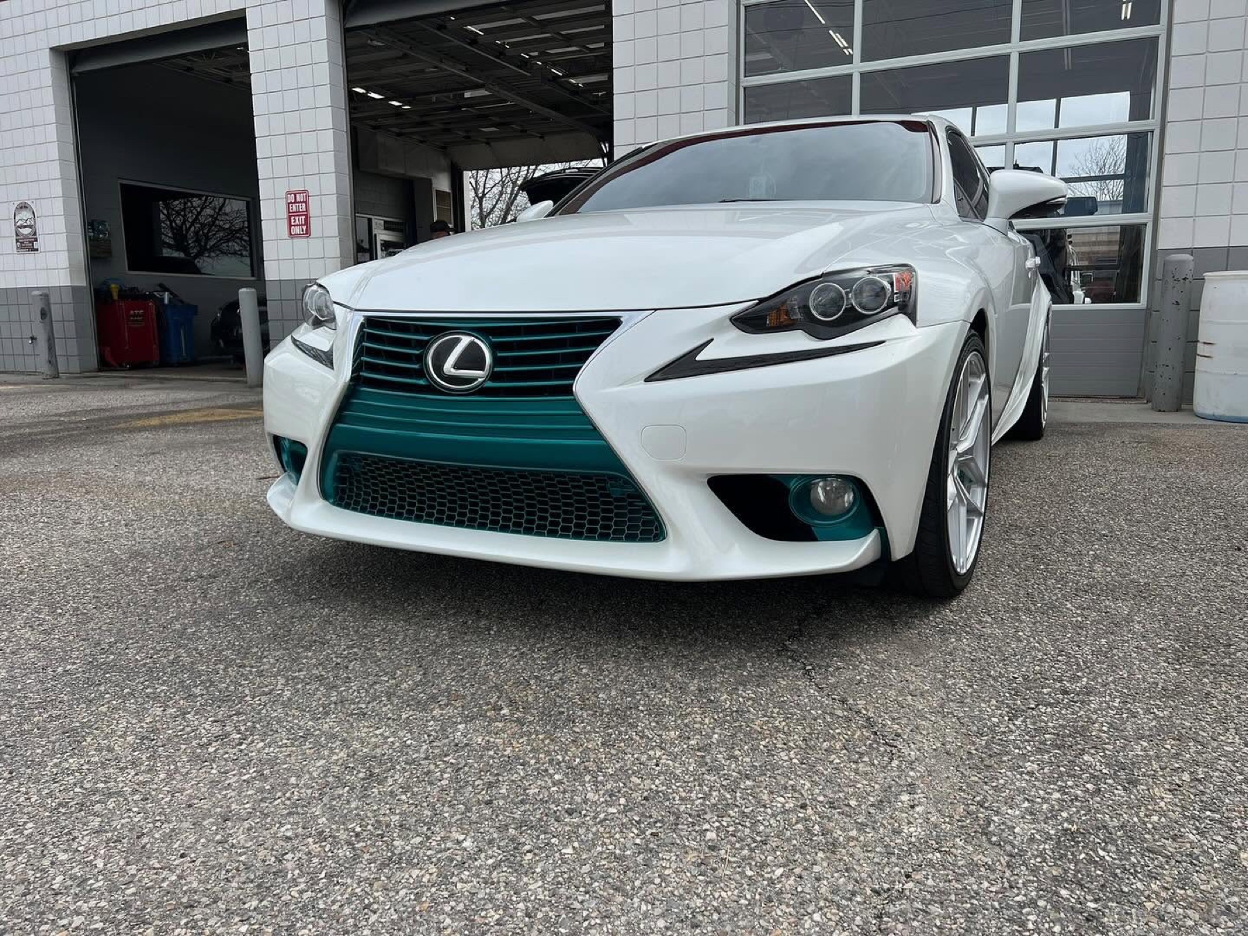 White Lexus with custom teal grille accents outside the shop