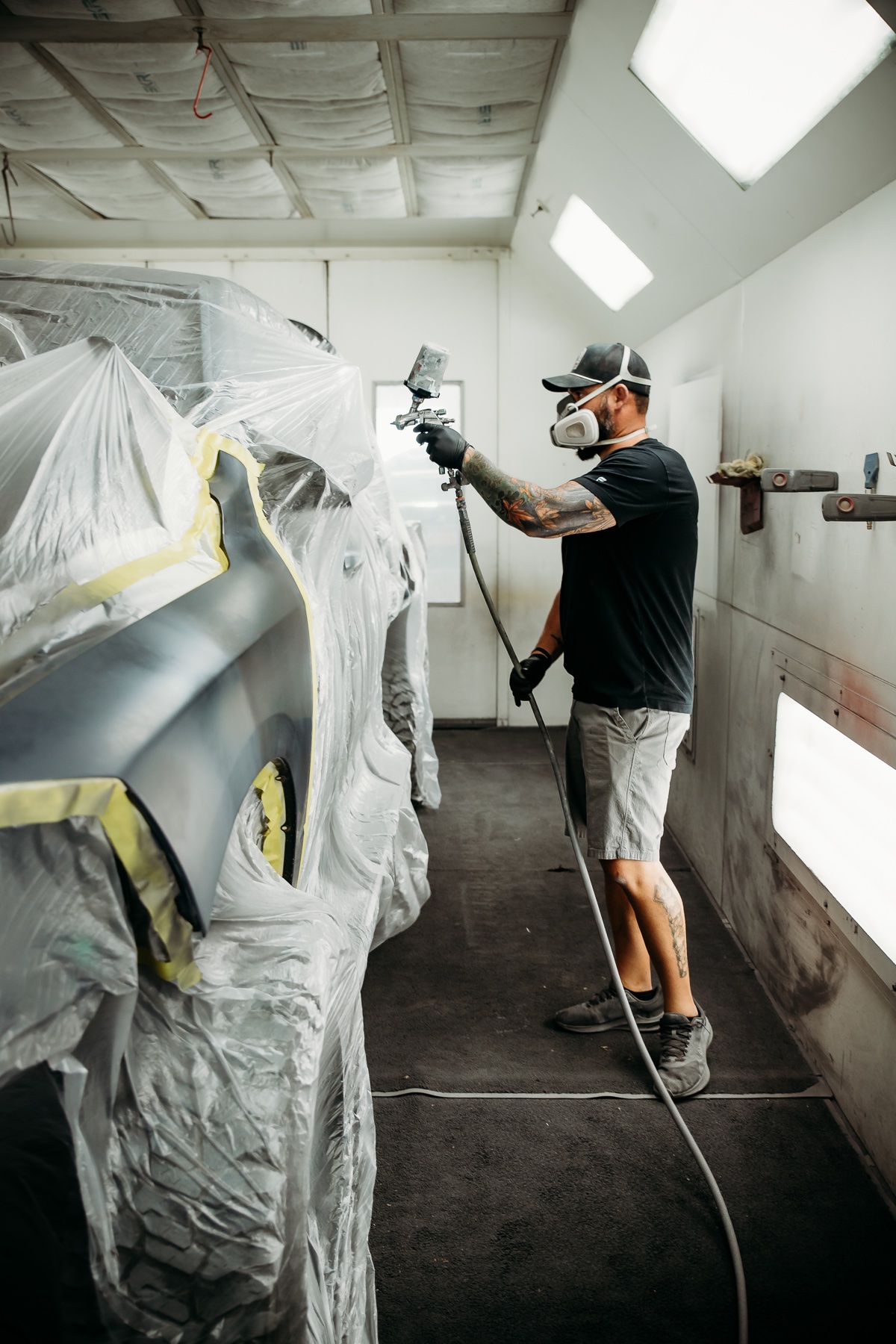 Jordan spraying a masked vehicle inside the paint booth