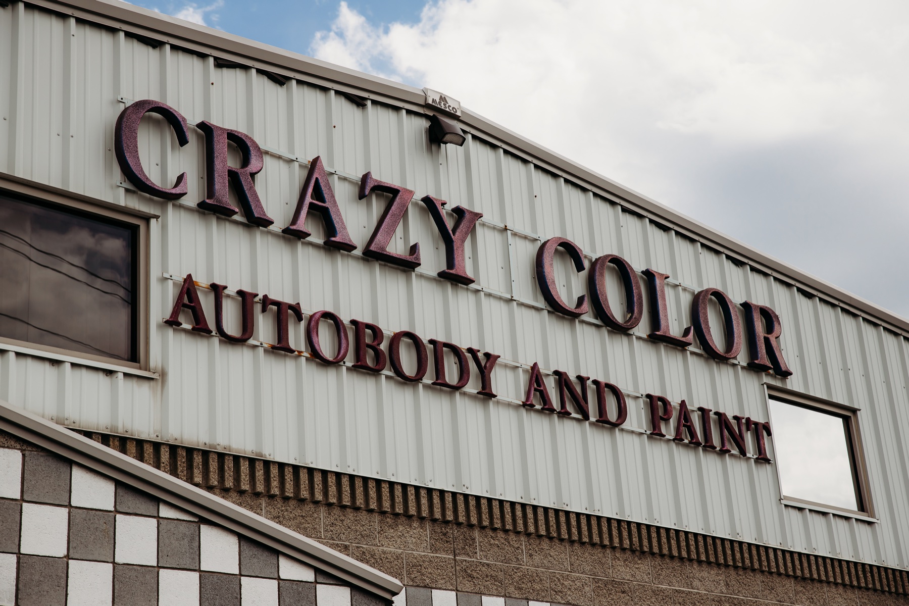 Crazy Color Auto Body and Paint building sign beneath a blue sky
